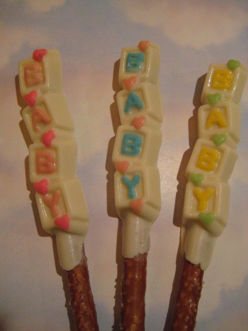 Three white chocolate-covered pretzel rods from the "24-Chocolate Covered Pretzel Rods-BABY Verse-Baby Shower Favors," each featuring pastel letters spelling "BABY" and tiny hearts.
