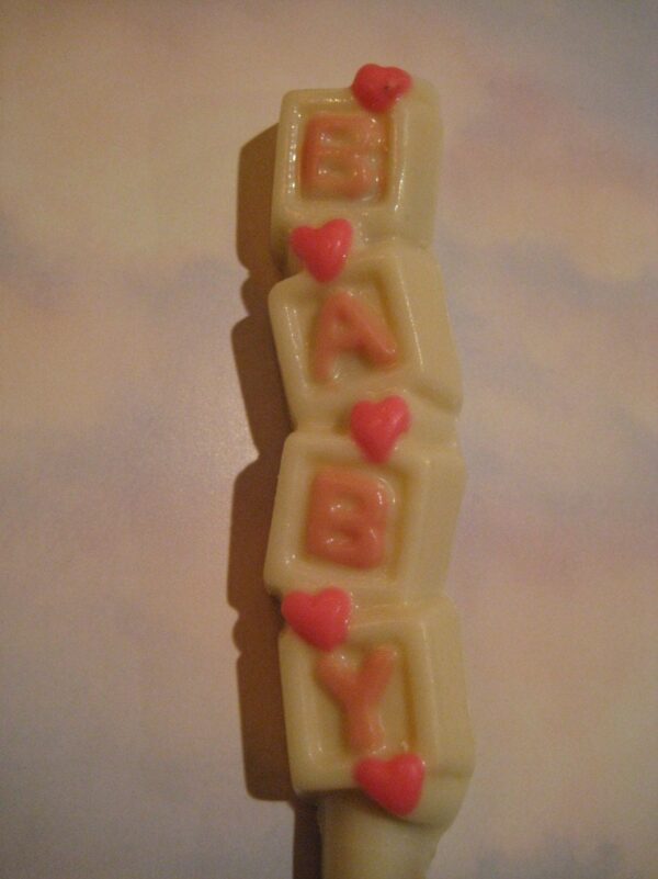 White chocolate-covered pretzel rod with "BABY" in pink letters and small heart shapes.