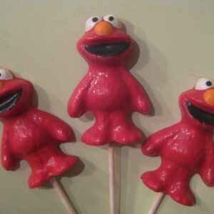Three Elmo-shaped chocolate lollipops arranged on a light green background.
