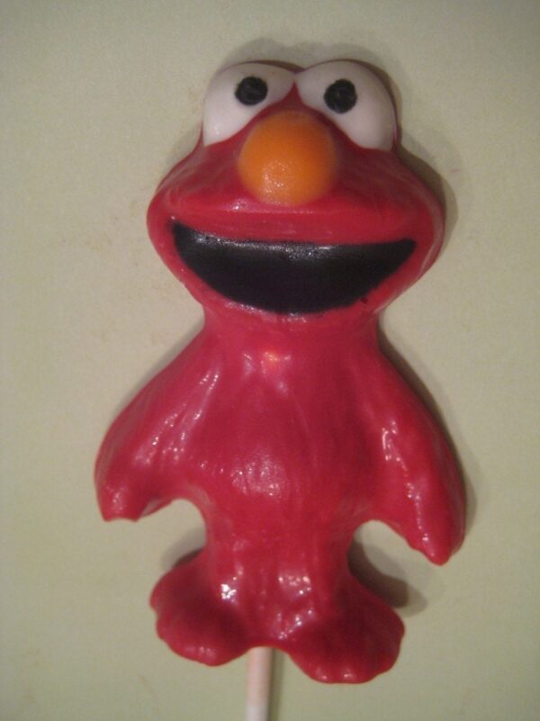 A chocolate Elmo lollipop with eyes, a grin, and an orange nose on a stick, perfect for birthday or children's party favors.