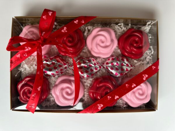 A boxed set of rose-shaped pink and red chocolates, plus three chocolate lips in heart foil, adorned with a red "Valentine's Day" ribbon. Product: 8-Chocolate Covered Oreo Roses For Anniversary/Birthday/Valentine Gift Box.