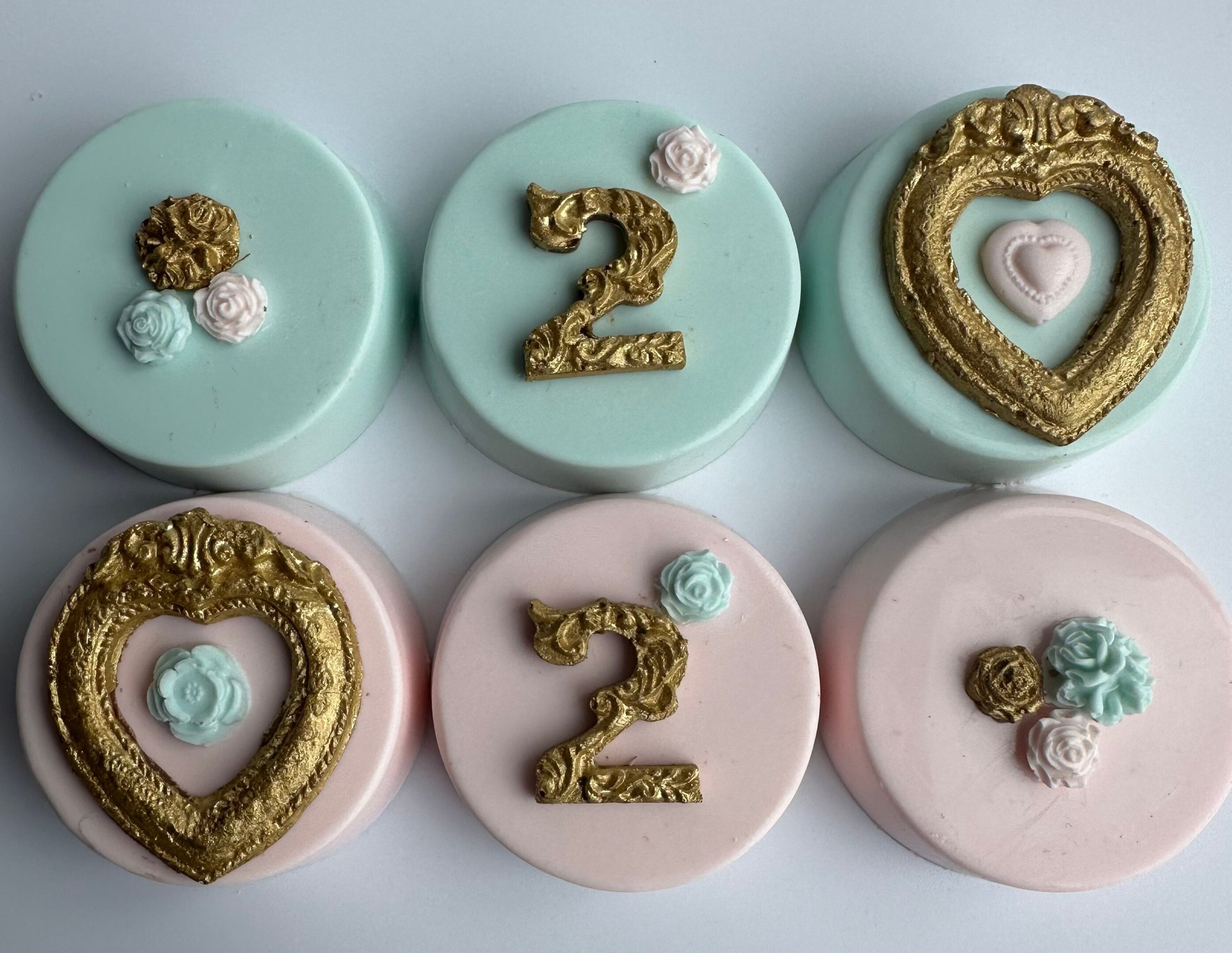 Six chocolate-covered Oreos from the "12-Gold Frame Chocolate Covered Oreos For Girl Birthday/Boy Birthday With Age" range, decorated with pastel blue and pink frosting, feature either golden numbers '2' or heart frames, along with rose embellishments.