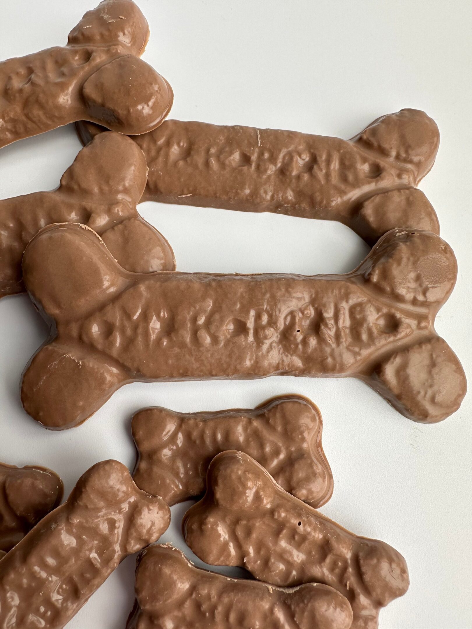 6-bags of chocolate dog bones for birthday/gag gift/treats scattered on a white surface.