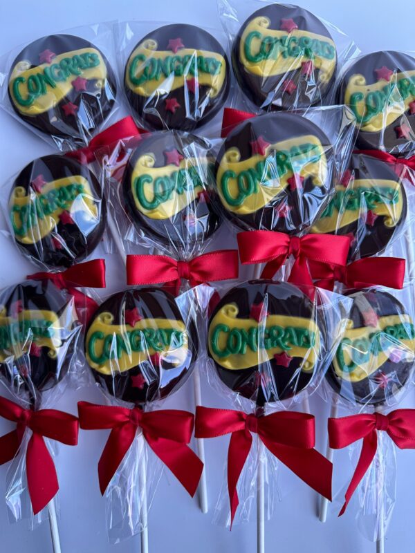 12-Congratulations Chocolate Lollipops are wrapped in plastic with red bows and feature a design that says "Congrats" in green and yellow.