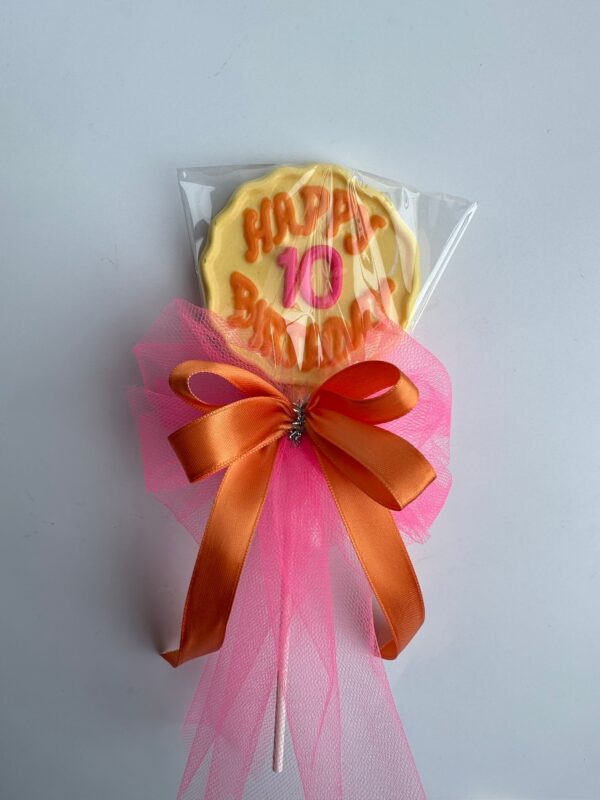 12-Happy Birthday Chocolate Lollipop with "Happy 10 Birthday" icing, decorated with pink tulle and orange ribbon bow, wrapped in clear plastic.