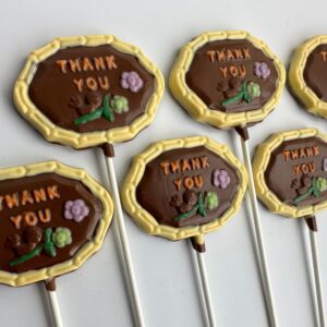 Five "Thank You" chocolate lollipops featuring colorful tree and flower designs on white sticks.