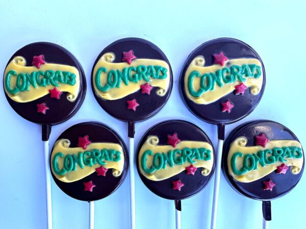 A set of 12 "Congratulations" chocolate lollipops featuring yellow icing text, red star decorations, and a light blue base.