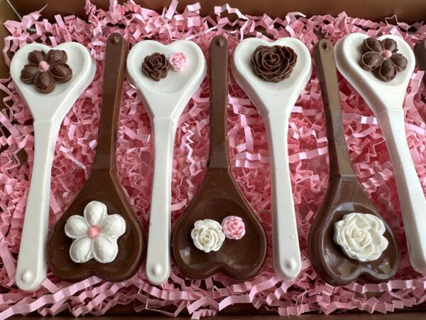 Chocolate Heart Spoons Gift Box with floral decorations, displayed in a row on pink shredded paper.