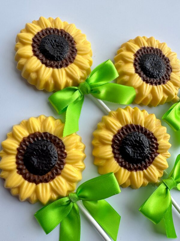 Four of the 12-chocolate sunflower lollipops feature yellow petals, brown centers, green bows, and white sticks. Perfect for wedding favors, showers, or birthdays.