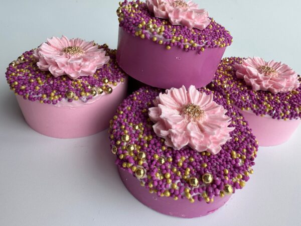 Four pink and purple chocolate-covered Oreos with flower designs and small beads, perfect for wedding or shower favors.