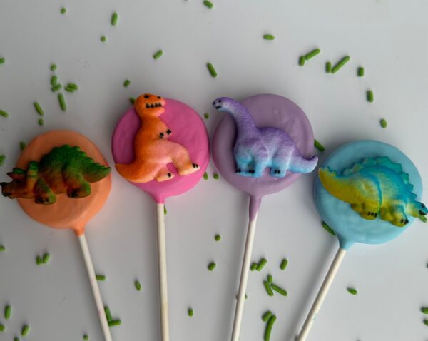 Four Oreo pops in orange, pink, purple, and blue with green sprinkles from the 12-Dinosaur Chocolate Covered Oreo Pops collection.