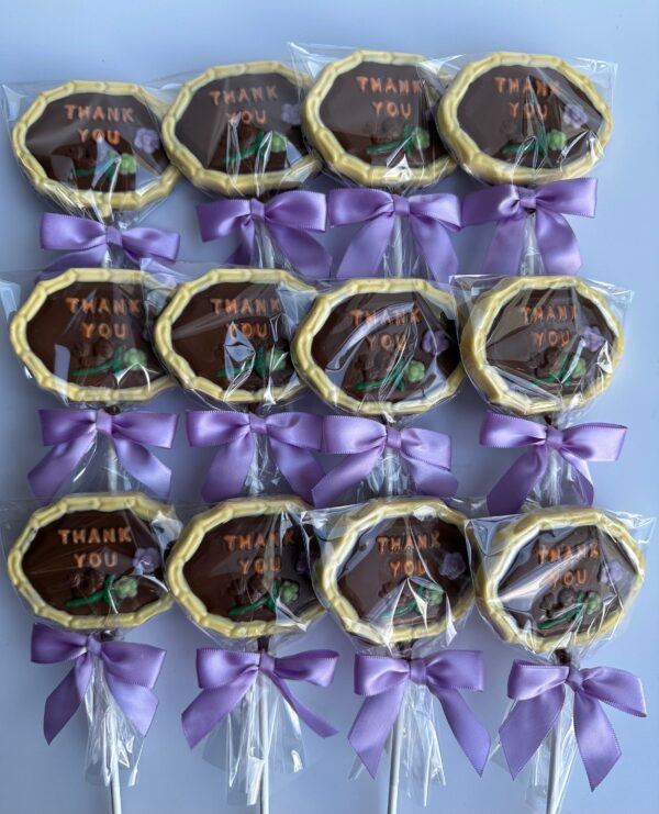 Twelve 12-Thank You Chocolate Lollipops wrapped in plastic, each with "Thank You" and adorned with purple bows.