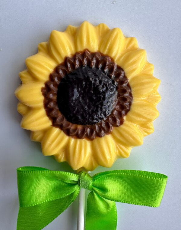 A lollipop from the "24-Chocolate Sunflower Lollipops for Wedding/Shower/Birthday Favor" collection features a sunflower shape with yellow petals, a dark center, and a green ribbon tied around the stick.