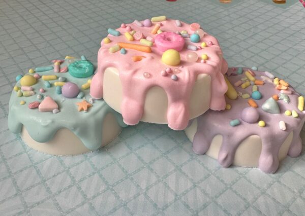 Three drippy chocolate cakes topped with chocolate-covered Oreos are stacked on a light blue checkered tablecloth, perfect for a birthday party or baby shower.