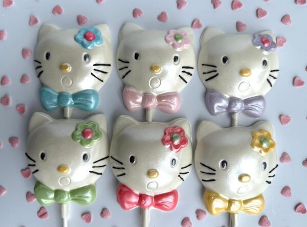 Two rows of six white chocolate lollipops, "Say Hello To My Sparkling Kitty Kat," feature cat shapes with pastel bows and flowers. The background is adorned with small heart shapes.