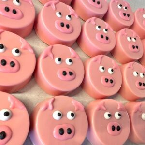 Rows of 24-Pink Pig Chocolate Covered Oreo Favors, each with detailed pig faces featuring eyes, snouts, and ears.