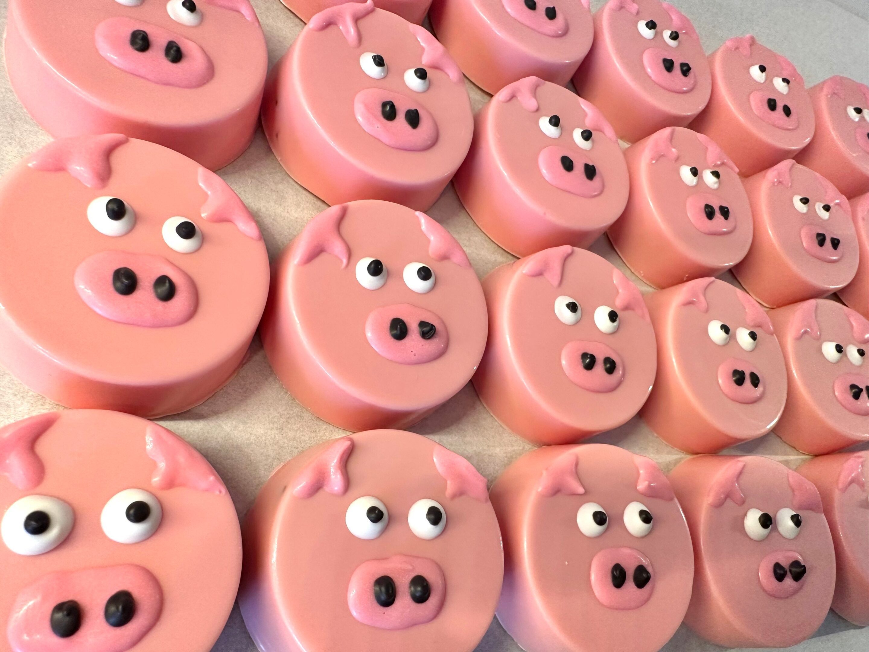 Rows of 24-Pink Pig Chocolate Covered Oreo Favors, each with detailed pig faces featuring eyes, snouts, and ears.