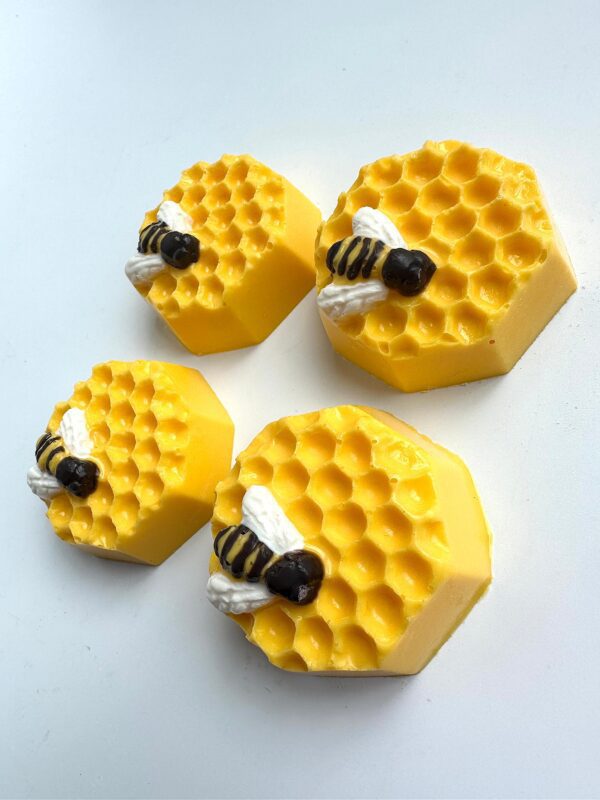 Four yellow hexagonal chocolate-covered Oreo cookies with bee decorations, arranged on a white background.