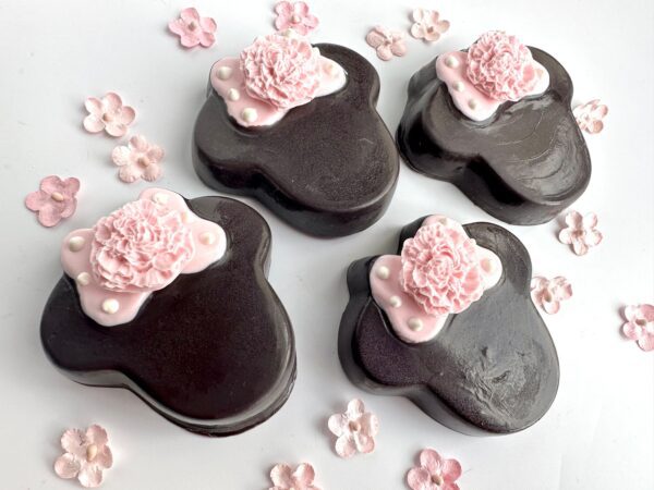 Four bear-shaped chocolates, adorned with pink floral decorations and pearl accents, are surrounded by small pink flowers, all set against a white background. These are part of the "12-Minnie Chocolate Covered Oreos For Party Favors/Birthday Party/Baby Shower" collection.