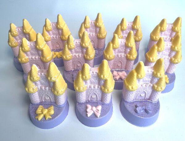 Rows of pastel castle-shaped soaps feature yellow towers, purple bases, and bows.
