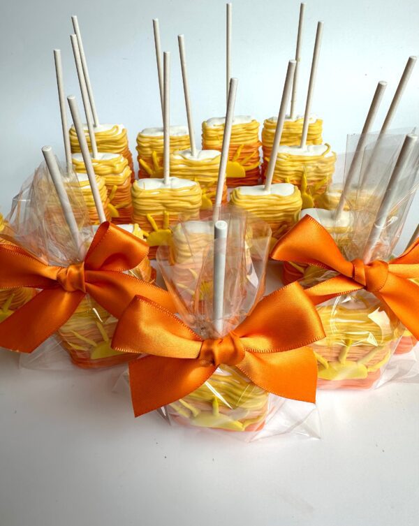 Sunset Ombré Chocolate Covered Rice Krispie Treats, with yellow and orange drizzle, wrapped in clear plastic and topped with an orange bow, neatly arranged in rows for birthday parties or baby showers.