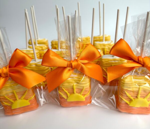Sunset Ombré chocolate-covered Rice Krispie treats, wrapped in plastic bags and tied with orange ribbons, are arranged in rows.