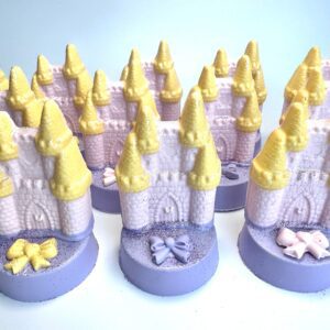 Pastel-colored, castle-shaped soap bars with yellow roofs and decorative bows sit atop chocolate-covered Oreos in a set of 12, ideal for princess, rainbow, or unicorn parties.