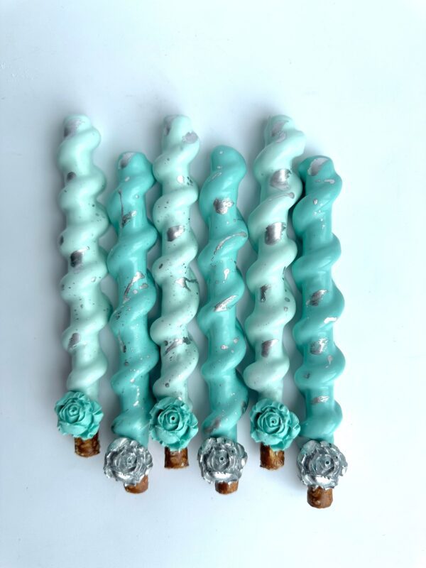 Six 12-Tiffany Blue and Silver chocolate-covered caramel pretzels feature blue, teal, and white icing adorned with silver spots and floral designs at one end, neatly aligned on a white background.