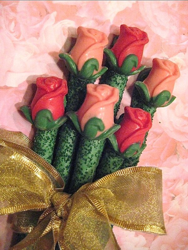 A bouquet of 24 chocolate-covered pretzel rods shaped like long-stem roses, tied with a gold ribbon against a pink floral background.