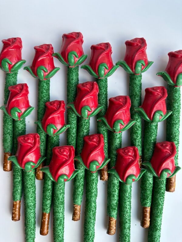 24 long-stem, rose-shaped chocolates cover pretzel rods with green stems on a white background.