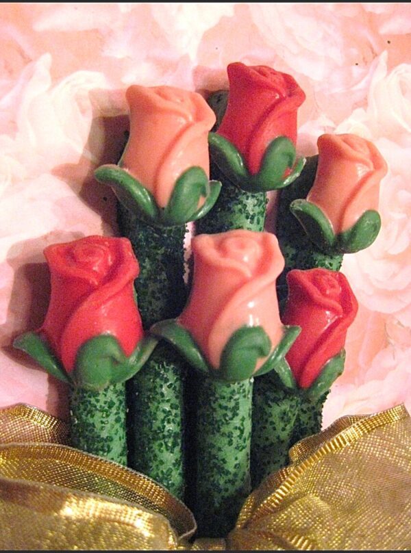 Chocolate-covered pretzel rods shaped like long-stem roses, featuring alternating red and pink buds with green leaves, arranged in a bouquet and wrapped with a gold ribbon.