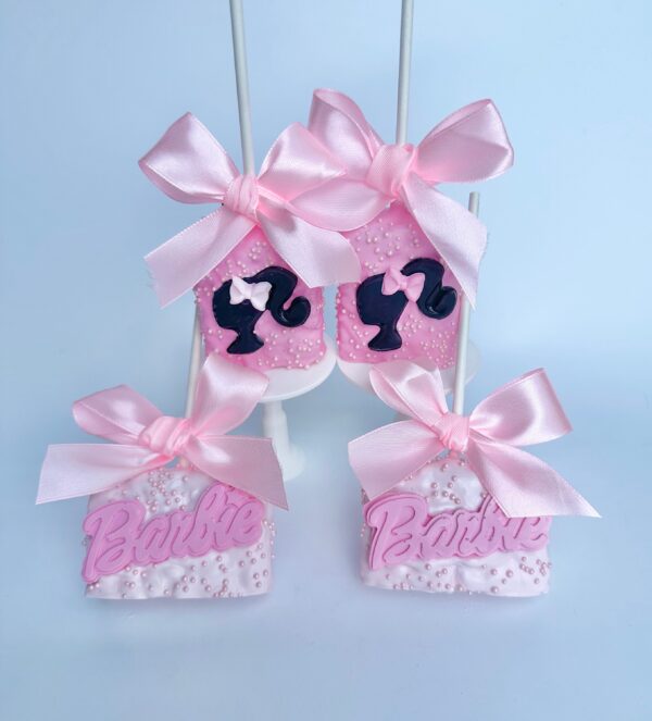 The 12 pink Barbie-themed chocolate-covered Rice Krispie treats are adorned with pink bows, silhouettes, and the word "Barbie," perfect for birthday or Barbie-themed party favors.