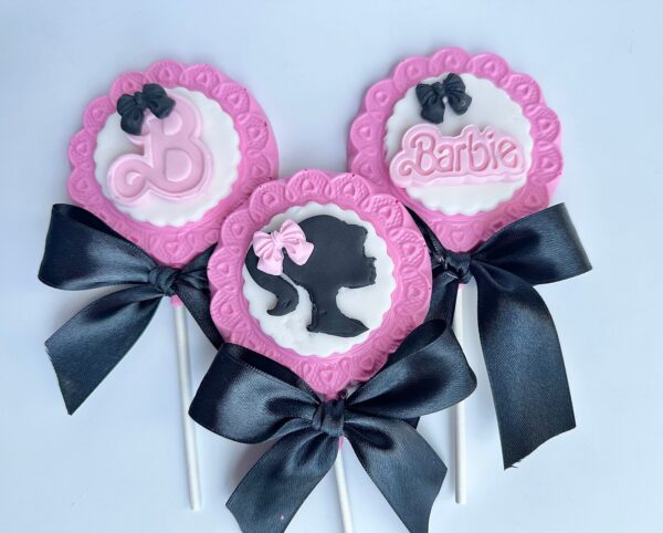 Three pink and black chocolate lollipops feature the Barbie theme with bows and include the logo, letter "B," and silhouette design.