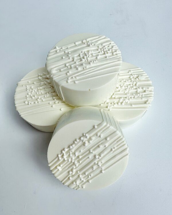 Four round, white chocolate-covered Oreos with diagonal textured lines and small dots on top, arranged in a cluster against a plain background. Perfect for weddings, bridal showers, or birthday parties.
