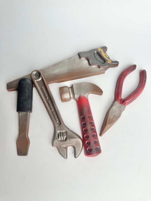 Toy tools including a saw, pliers, wrench, screwdriver, and hammer with red and brown accents are part of the 5 Piece Chocolate Tool Gift Set in a gold box, perfect for Dad's birthday or special occasions.