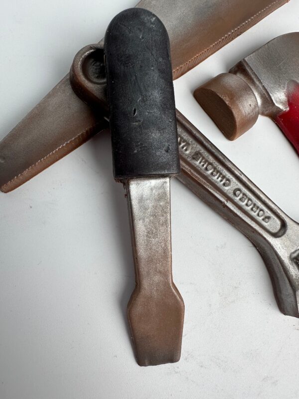 Three metal bottle openers, one with a black handle, from the 5 Piece Chocolate Tool Gift Set in Gold Gift Box, are arranged on a white surface.