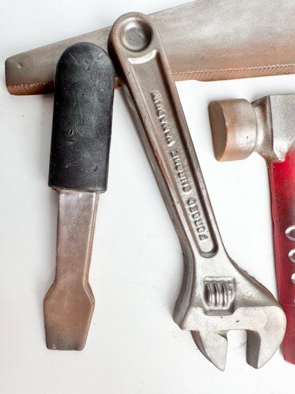 A 5-piece chocolate tool gift set shaped like a saw, screwdriver, adjustable wrench, hammer, and one more tool, beautifully displayed in a gold box—perfect for birthdays and special occasions for Dad.