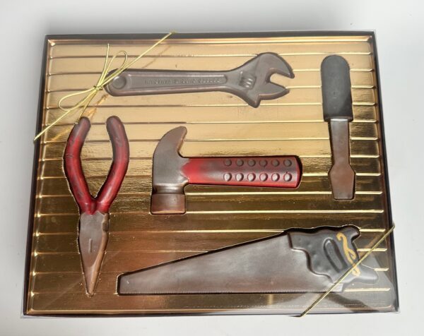 A 5 Piece Chocolate Tool Gift Set, including a wrench, pliers, hammer, flathead screwdriver, and saw presented in a gold gift box.