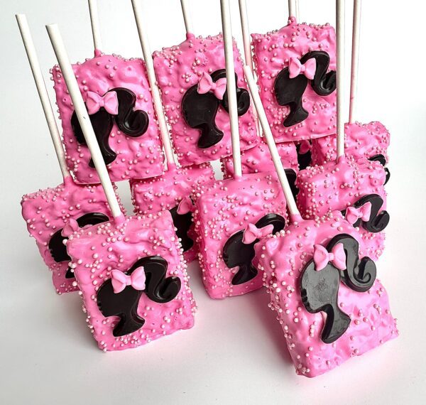 Rice Krispie treats on sticks, covered in pink chocolate and sprinkles, topped with black silhouette designs and pink bows.