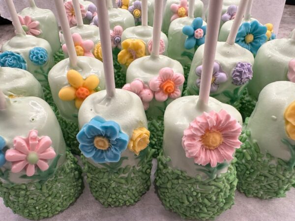 12-Flower Garden Themed Chocolate Covered Double Marshmallow Pops feature green marshmallows adorned with colorful flower decorations and sprinkles.