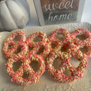 Strawberry shortcake pretzel twists are arranged on a decorative plate beside a small pumpkin and a "sweet home" sign.