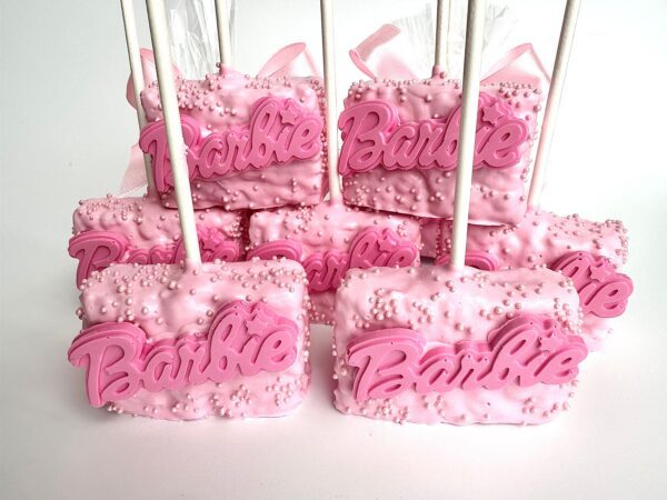 Pink chocolate-covered Rice Krispie treats on sticks, with "Barbie" in pink lettering and adorned with pink and white candy pearls.