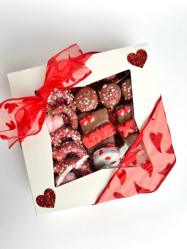 A Milk Chocolate Treat Gift Box adorned with heart designs and a red ribbon, perfect for anniversaries, sweethearts, Valentine's Day, or birthdays.