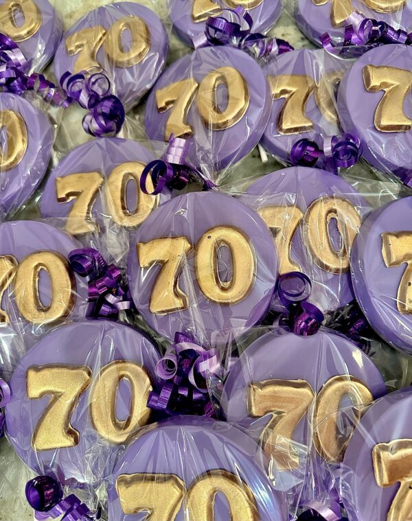 Purple "70" chocolate party favors for a 70th birthday or anniversary, wrapped in clear plastic with purple curling ribbons.