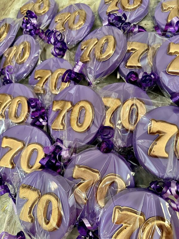 Purple and gold chocolate lollipops, shaped as the number 70, are wrapped in cellophane and secured with purple ribbons. These are part of the "12-Purple 70th Birthday/Anniversary Chocolate Lollipop/Party Favors/70th Birthday Party" collection.