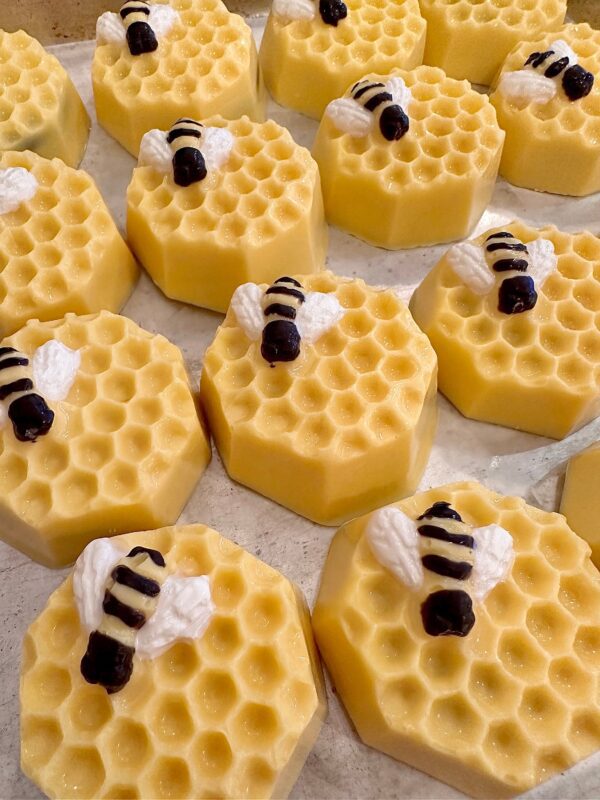 Honeycomb chocolate-covered Oreos with decorative bumble bees, arranged in rows.