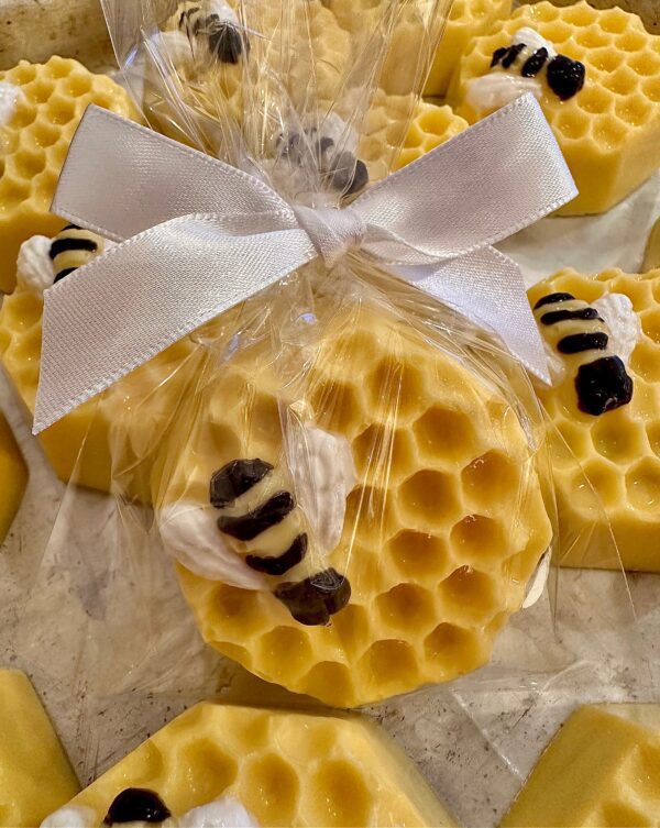 Honeycomb-shaped soap is wrapped with a white ribbon, adorned with small decorative bees, mimicking the style of 12-Sweet Honeycomb Chocolate Covered Oreos With Bumble Bees for a baby shower or party.