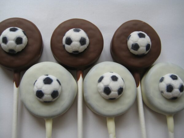 A row of four 12-Soccer Ball Chocolate Covered Oreo Lollipops against a white background.