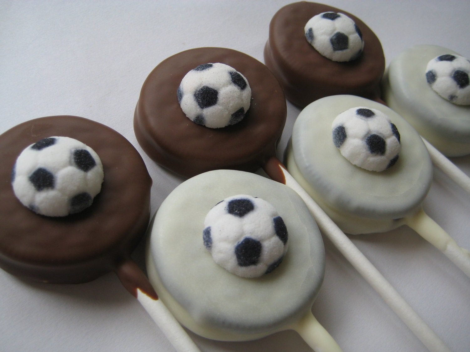 12-Soccer Ball Chocolate Covered Oreo Lollipops arranged with alternating dark and light colors on sticks.