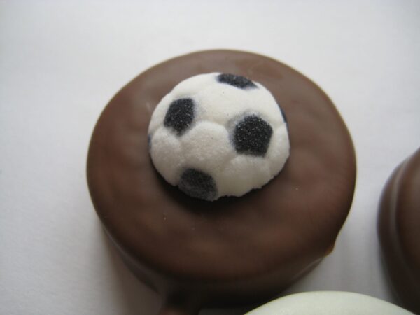 Oreo lollipop covered in chocolate and adorned with a small sugar soccer ball decoration.